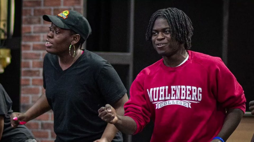 Two performers in motion during a rehearsal of Raisin.
