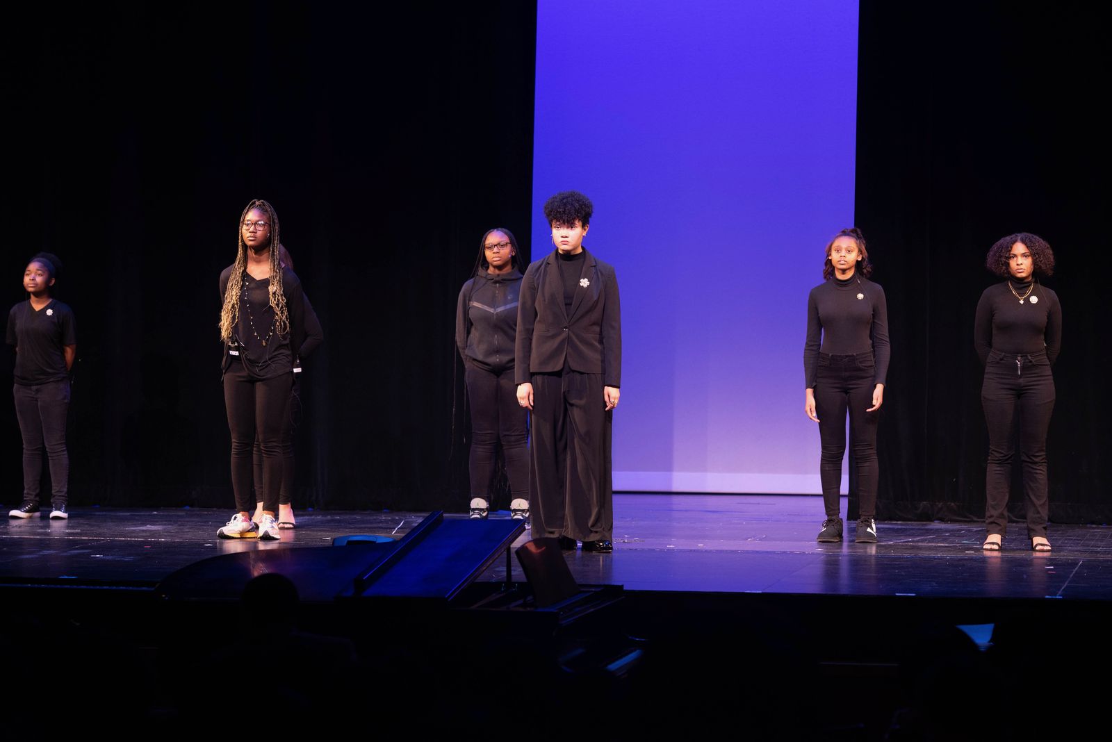 Young performers dressed in black standing on stage during a production
