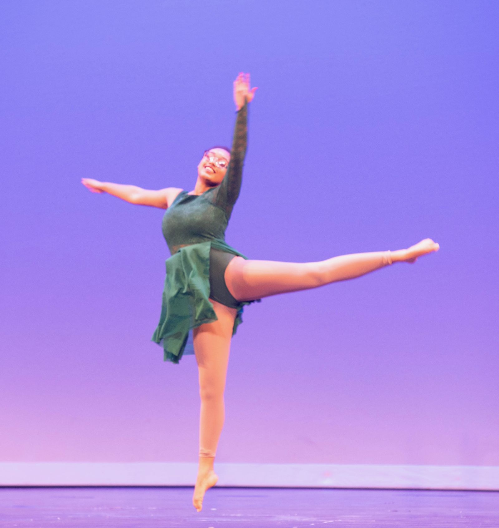 A dancer mid-leap on stage, arms extended