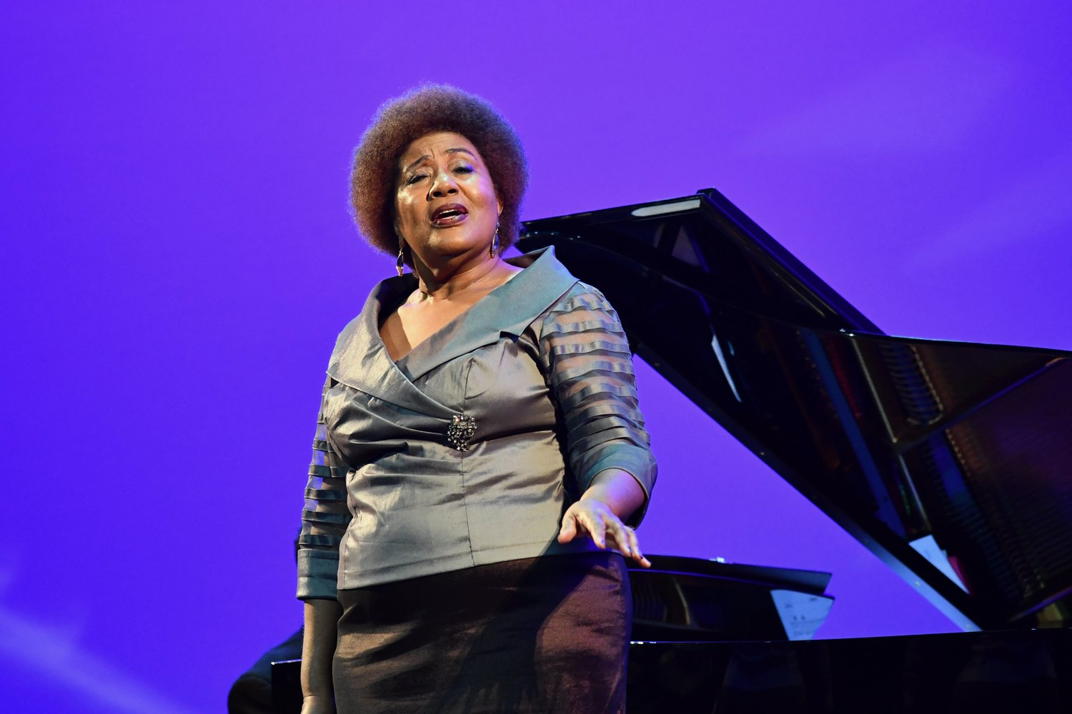 Priscilla Baskerville sings beside the grand piano at the Phylicia Rashad Auditorium dedication.
